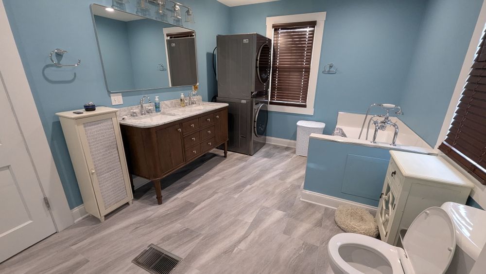 Bathroom with blue walls, wooden vanity, white toilet, and a refrigerator.