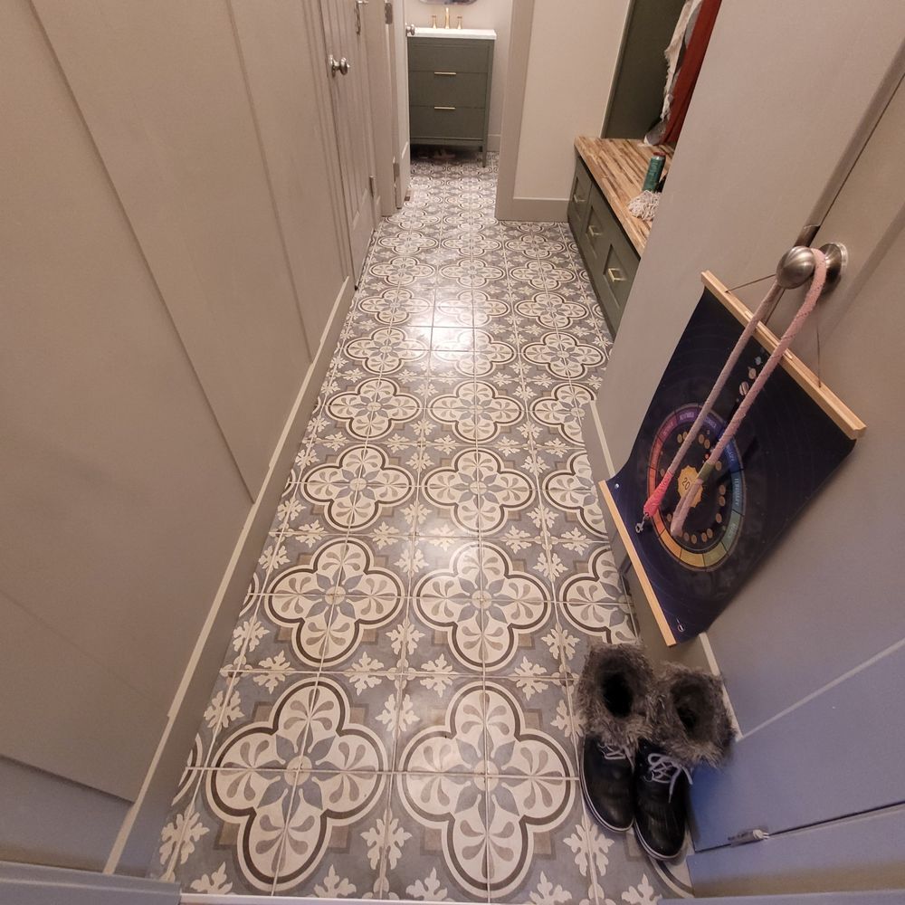 Hallway with patterned gray and white floor tiles, shoes, and a dartboard.