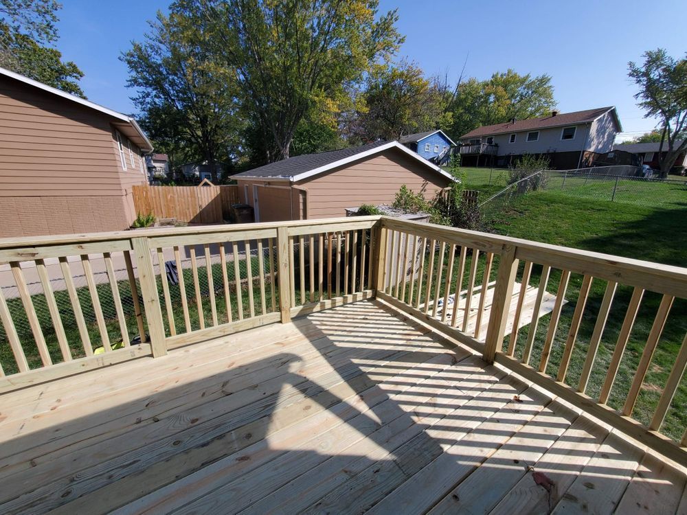 Wooden deck with railing in backyard, sunny day.