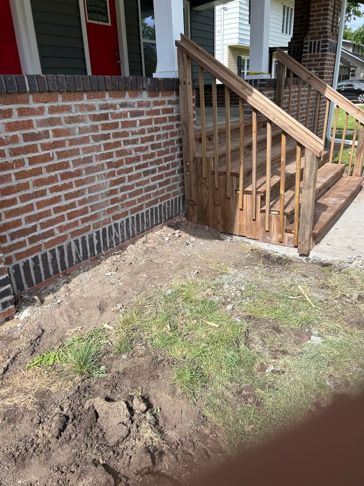 Brick building with wooden steps, dirt patch, and sparse grass.