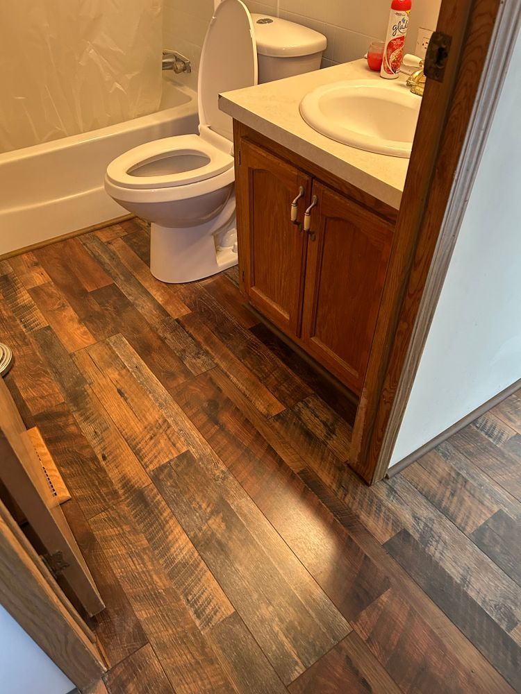Bathroom with wood-look flooring, toilet, vanity, and tub.
