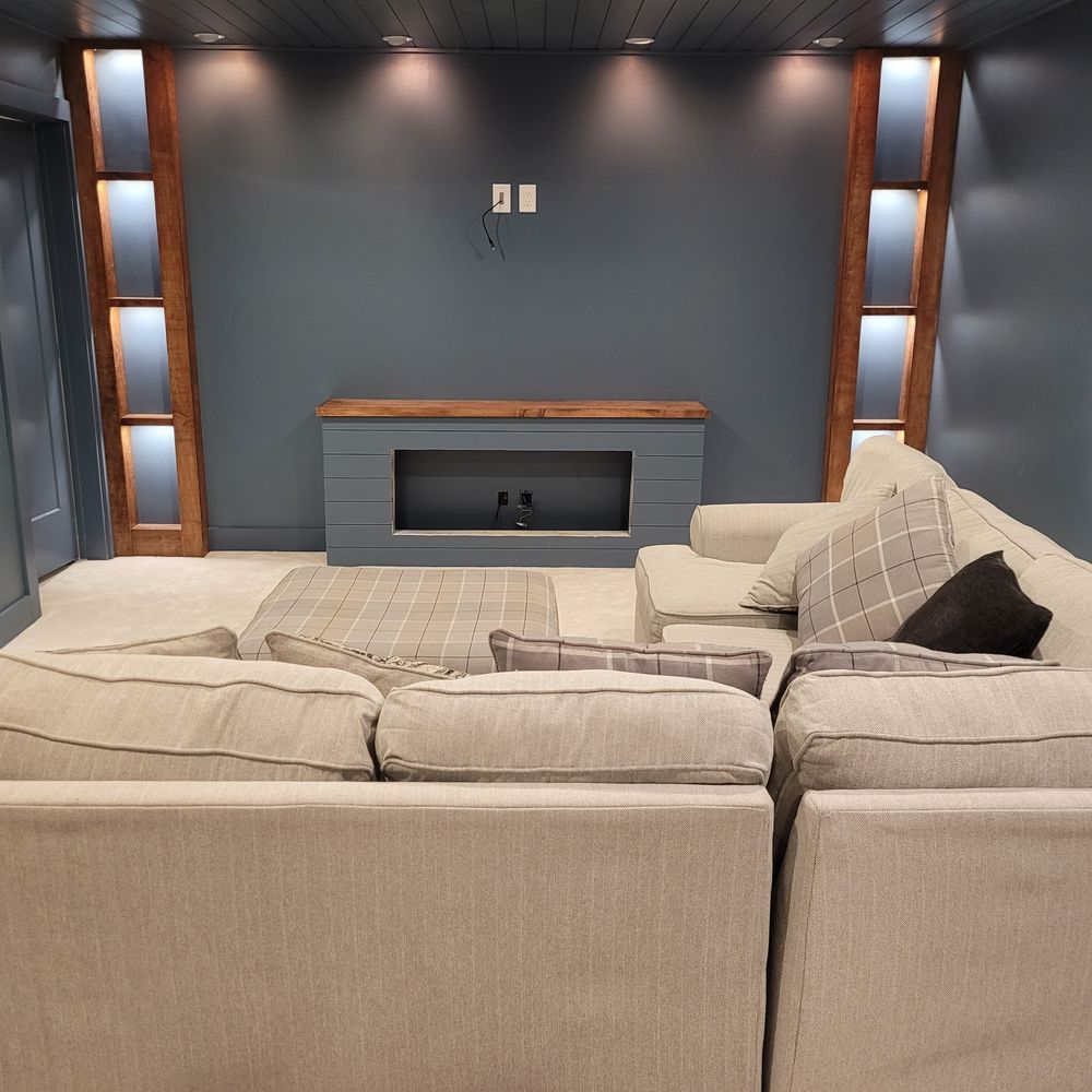 Living room with gray sectional sofa, fireplace, built-in shelving, and dark blue walls.
