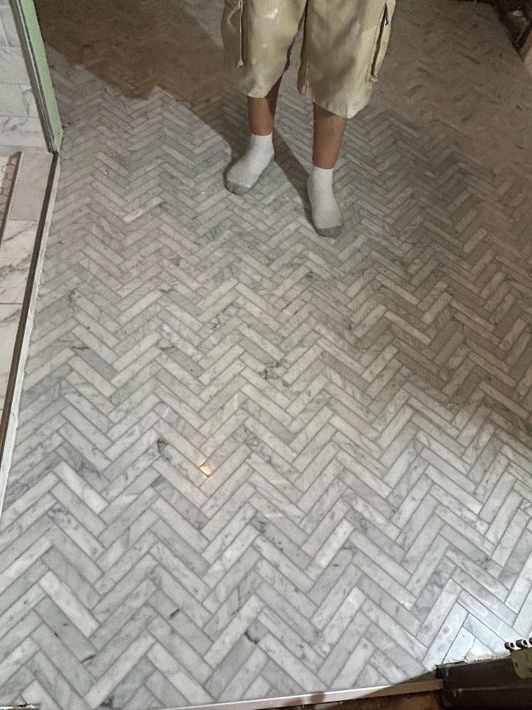 Person standing on a herringbone marble tile floor.