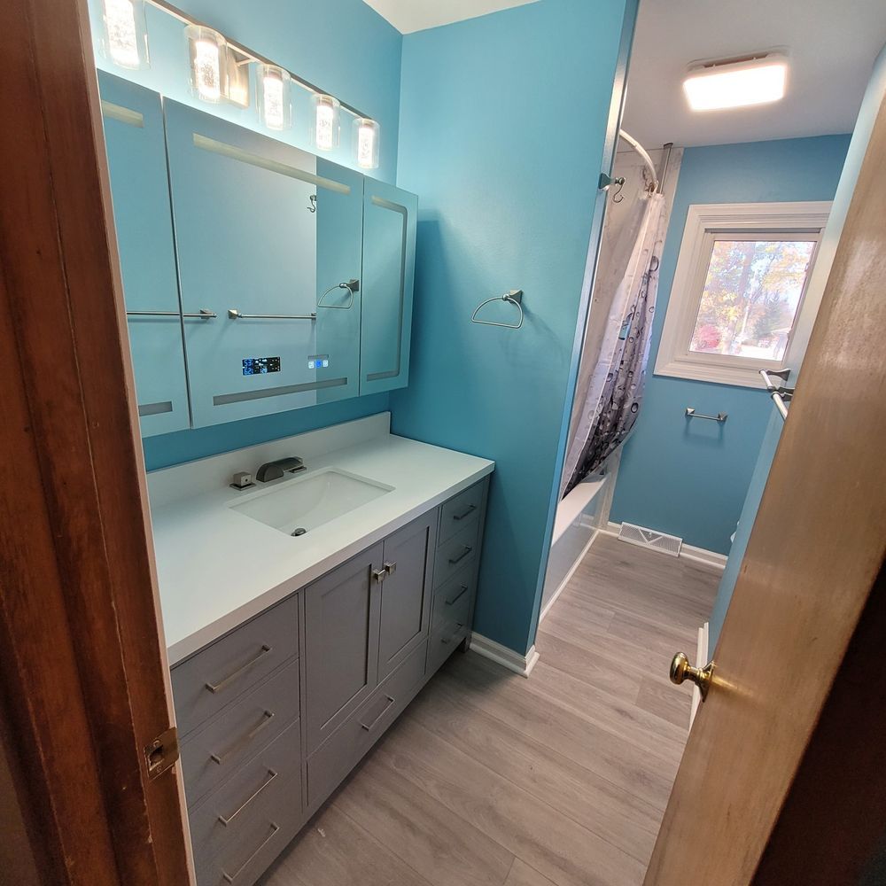 Bathroom with blue walls, grey vanity, white countertop, and a shower.