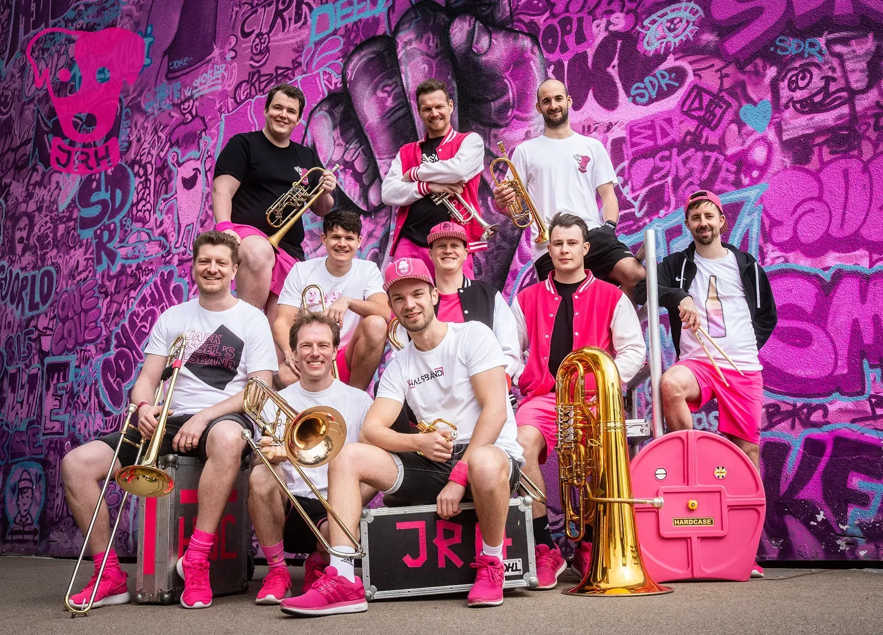 Eine Gruppe Männer posiert mit ihren Instrumenten vor einer Graffitiwand für ein Foto.