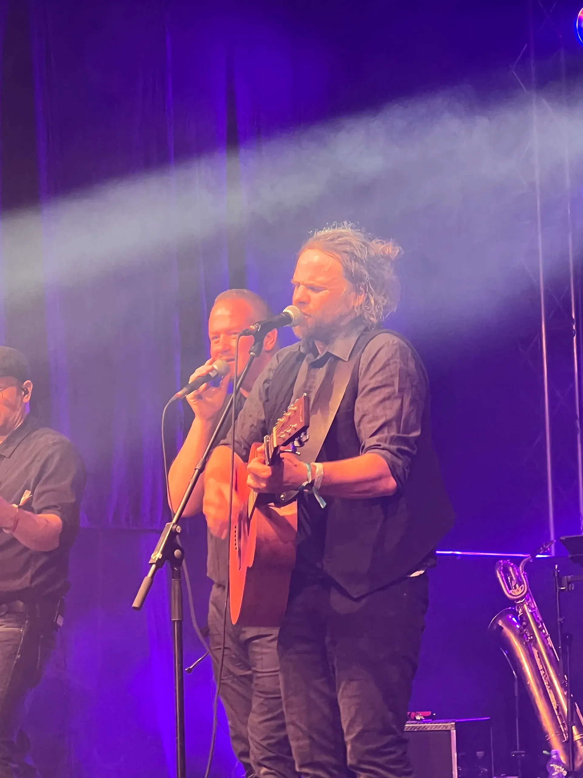 Auf einer Bühne spielt ein Mann Gitarre und singt in ein Mikrofon.