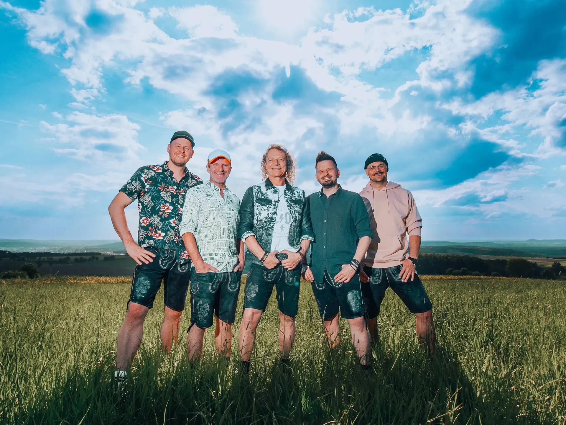 Die fünf Mitglieder der Band Troglauer stehen auf einer Wiese und schauen in die Kamera.
