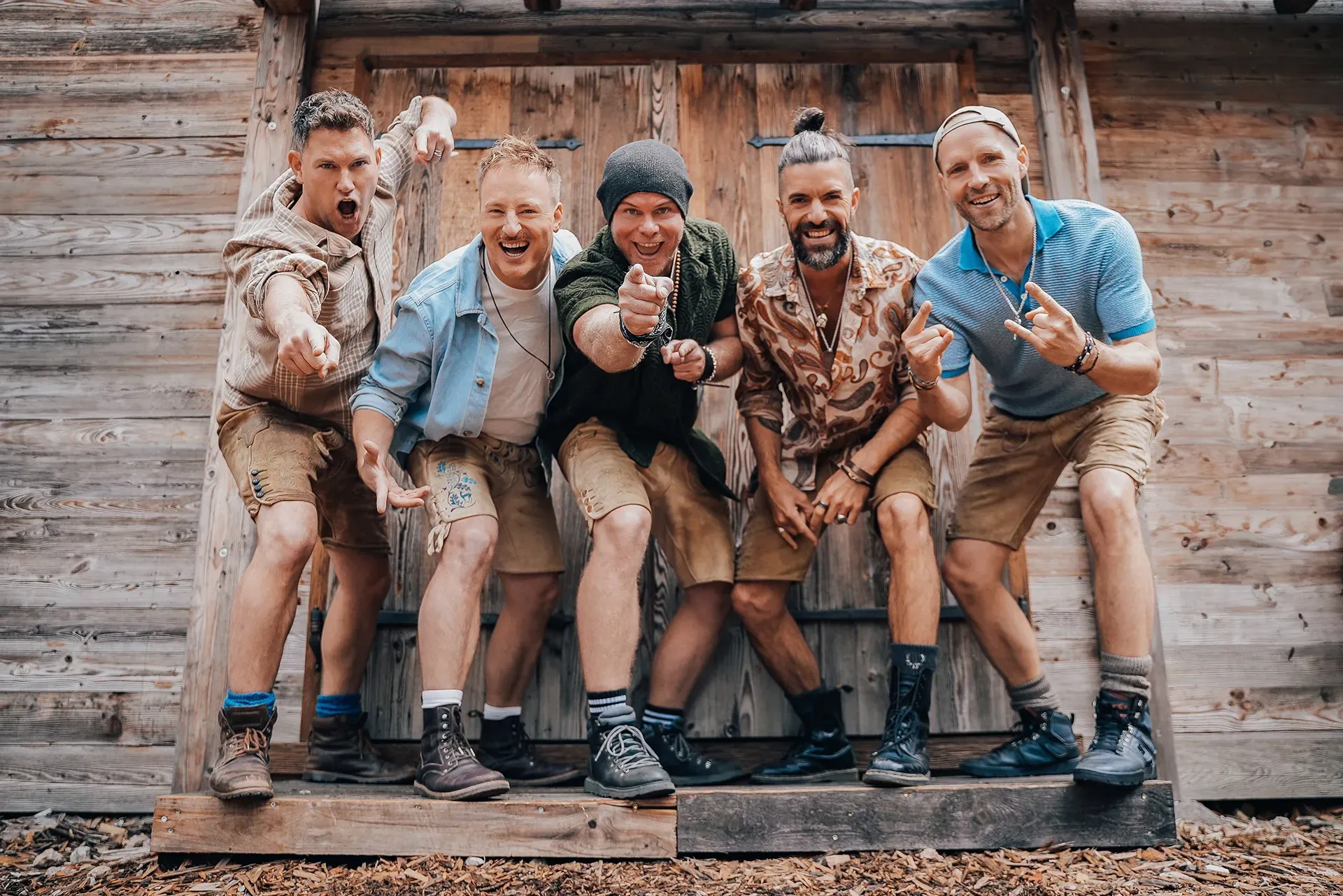 Eine Gruppe Männer posiert vor einem Holzgebäude für ein Foto.