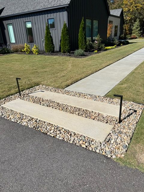 A house with a concrete walkway and steps in front of it.