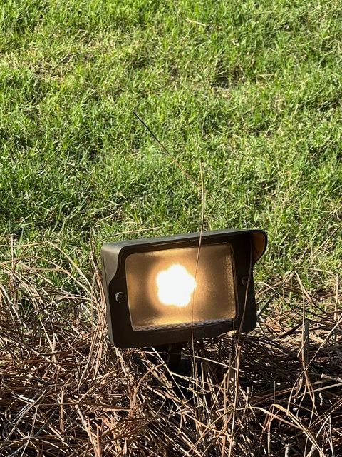 A spotlight is sitting in the middle of a grassy field.
