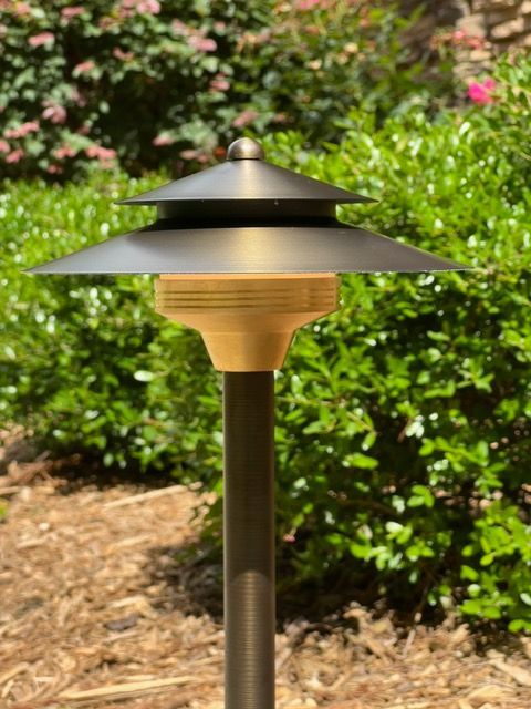 A lamp is sitting on a pole in the middle of a garden.