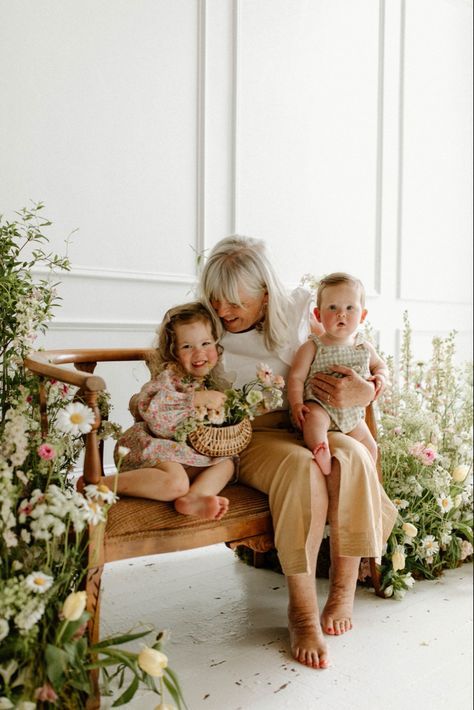 A woman is sitting on a bench holding two children.