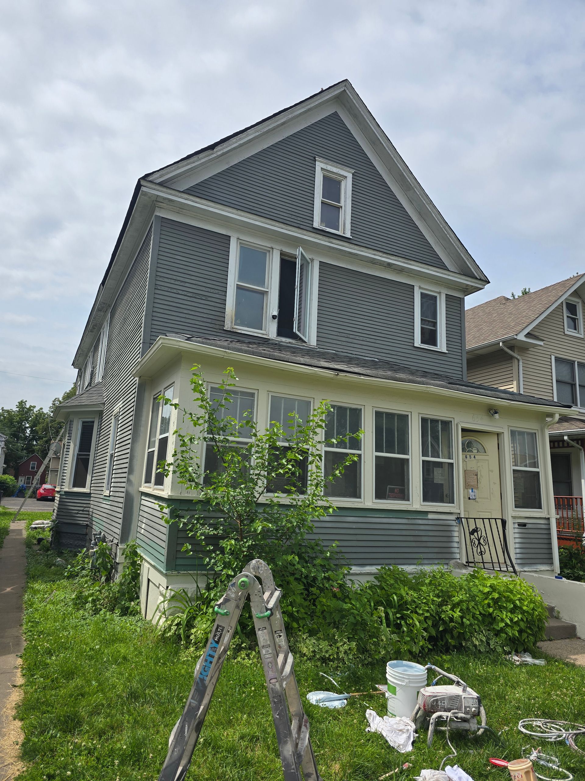 A house with a ladder in front of it is being painted.