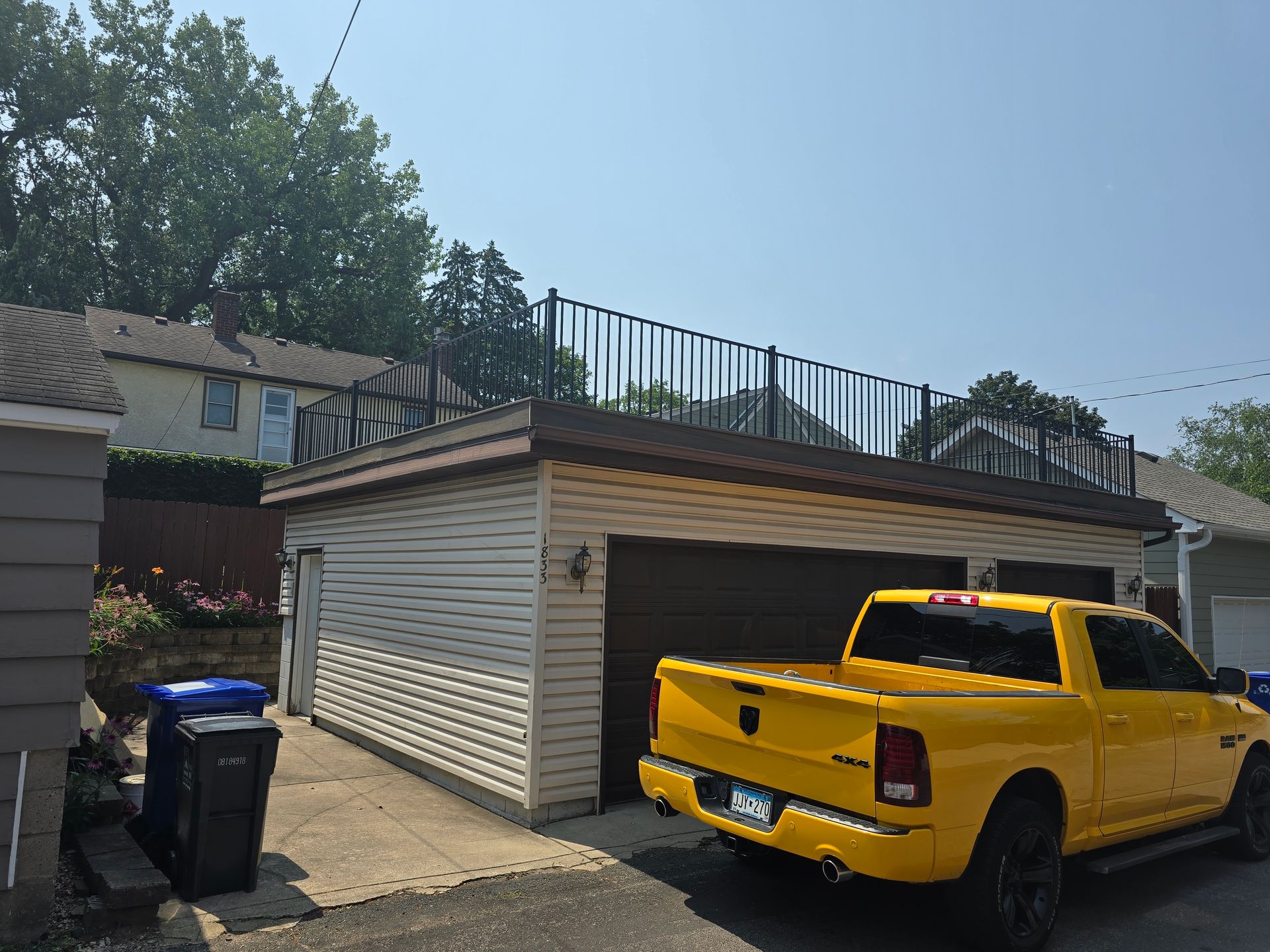 A yellow truck is parked in front of a garage.