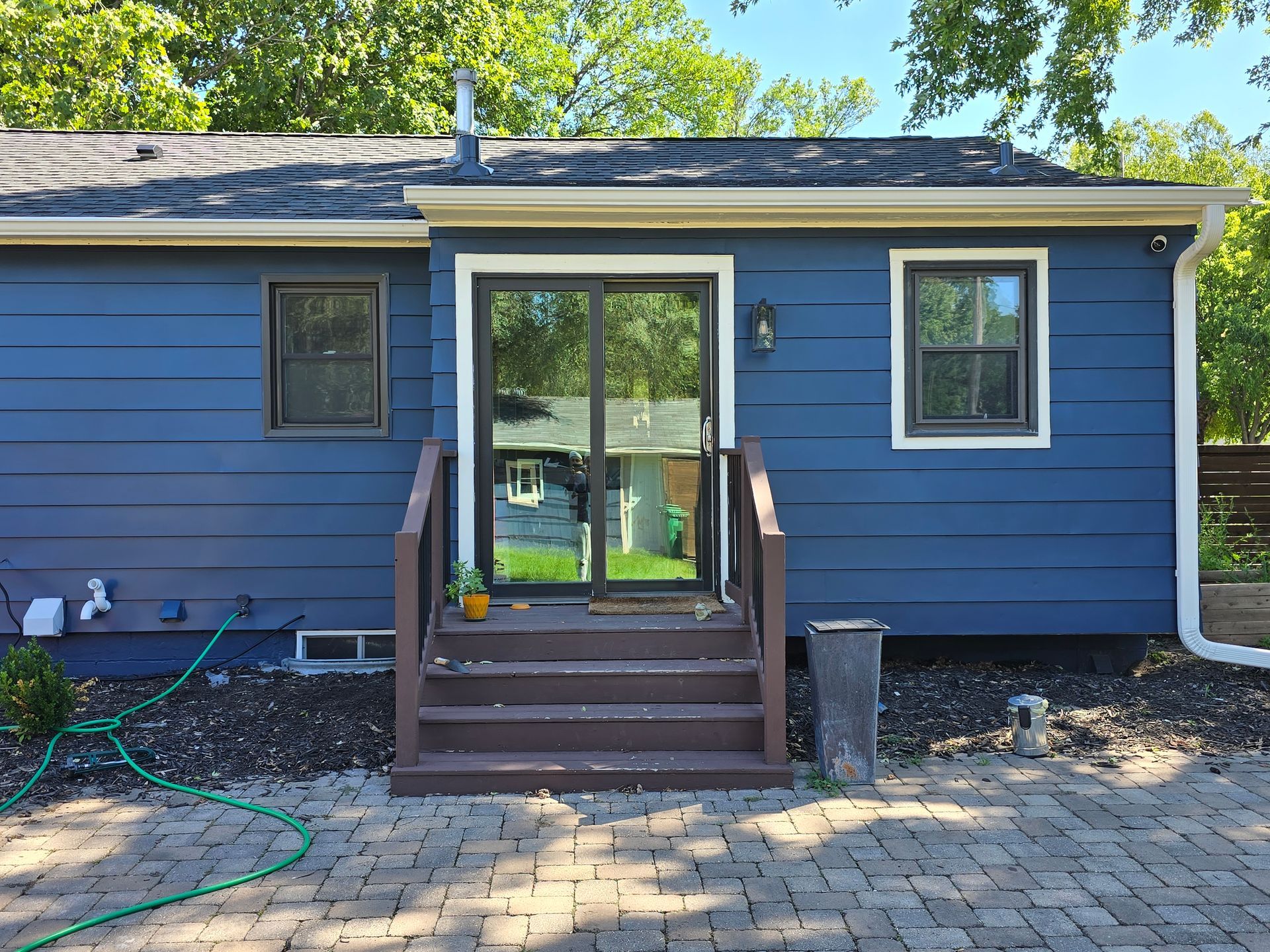 A blue house with a sliding glass door and stairs