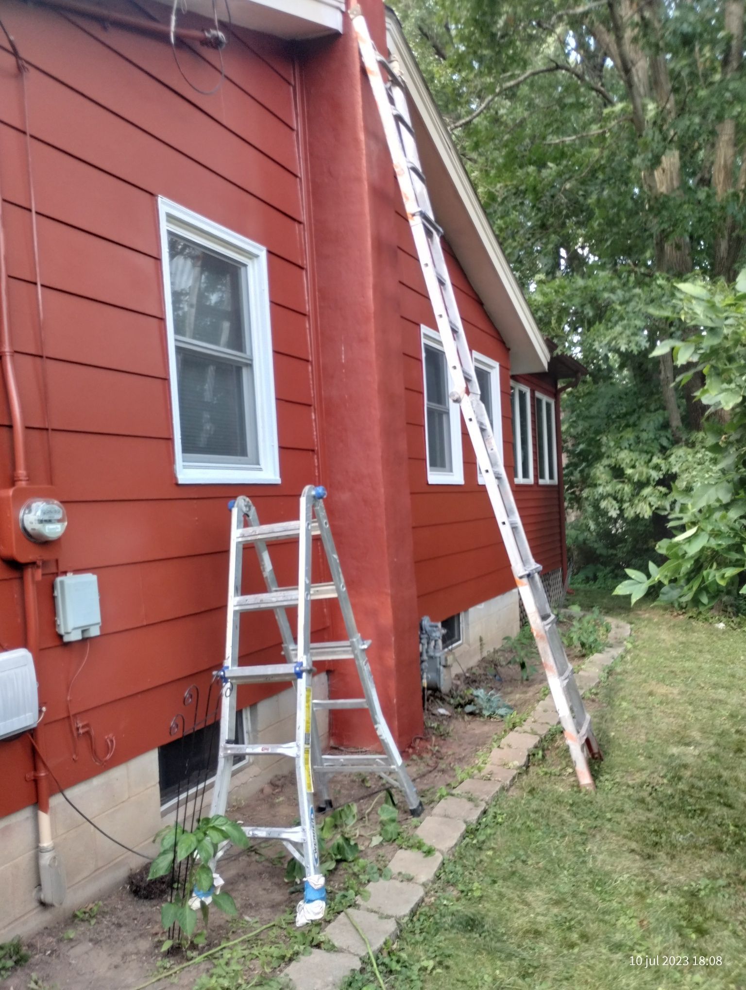 A ladder is leaning against the side of a red house