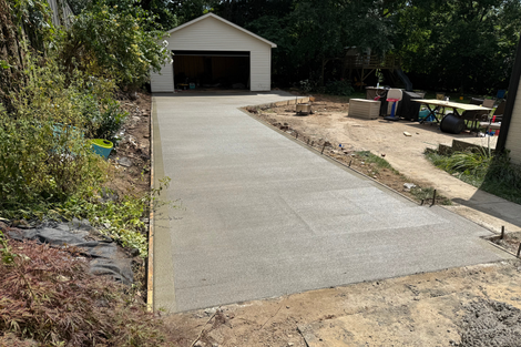 Newly poured concrete driveway leading to a garage. Overcast day.