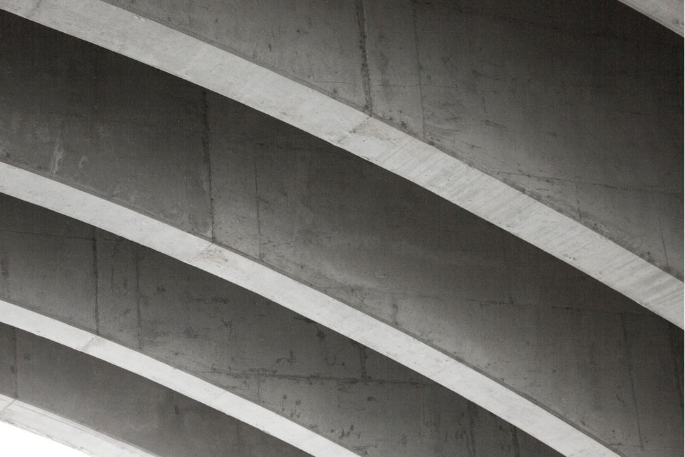 Concrete bridge underside with curved supports, in grayscale.
