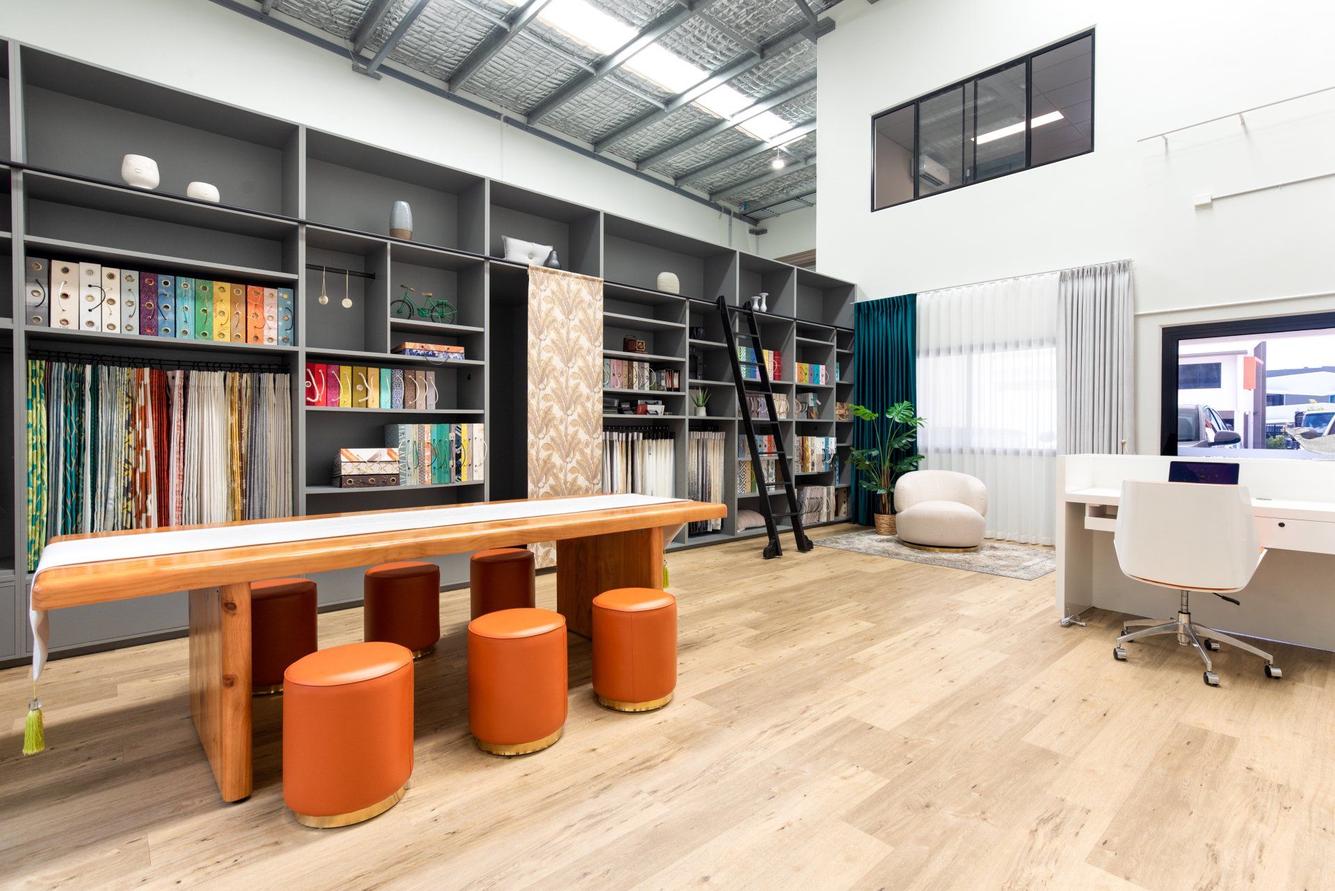 A large room with a table , chairs , stools and shelves.