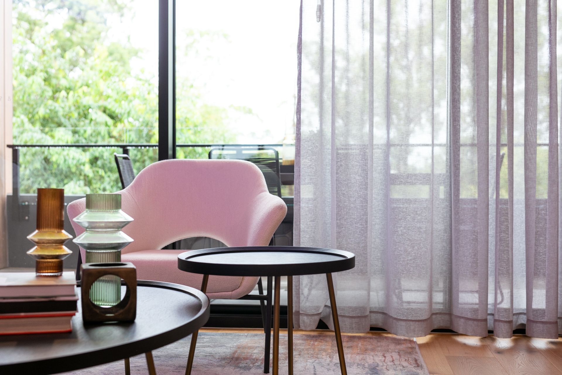 A living room with a pink chair , a table , and purple curtains.