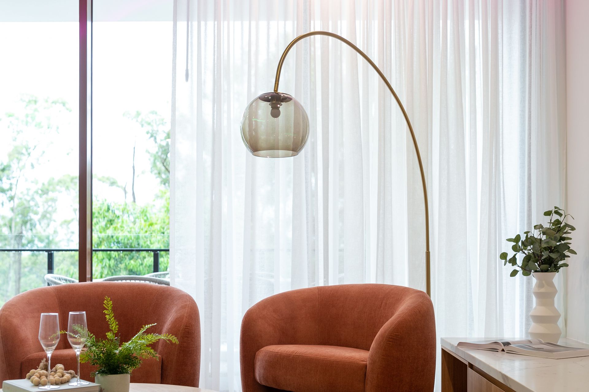 A living room with two chairs , a table , and a lamp.