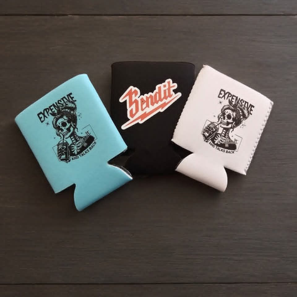 Three can coolers on a dark wood surface, with the center black one showing the Lindt logo.