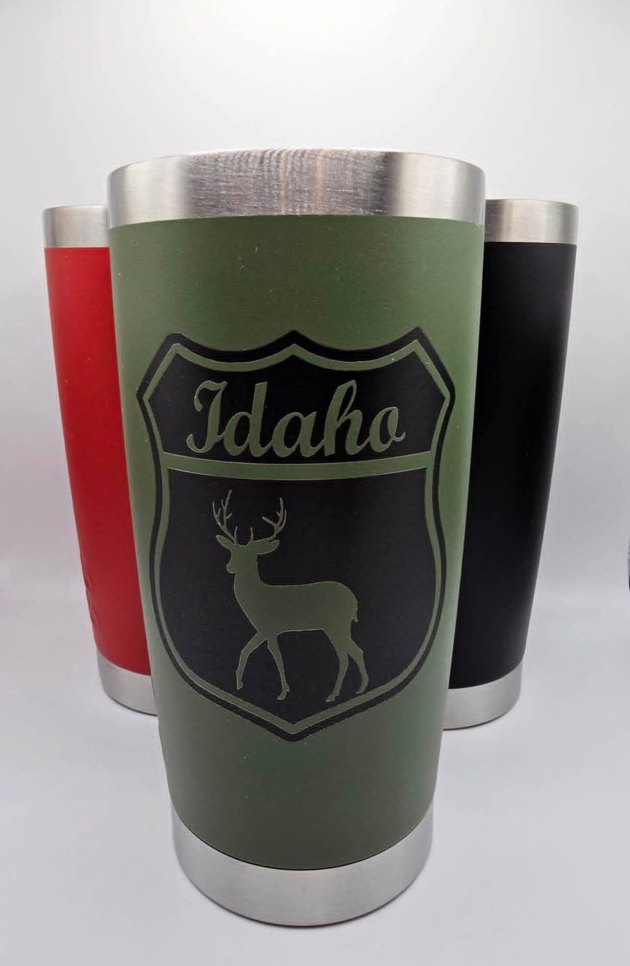 Three insulated tumblers; green Idaho deer design in front, with red and black tumblers behind.