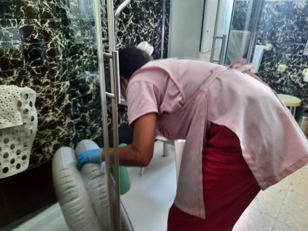 Uma mulher com um avental rosa está limpando um banheiro