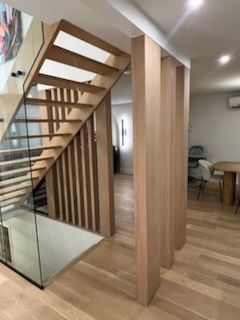 Un escalier en bois avec une rampe en verre dans une pièce.