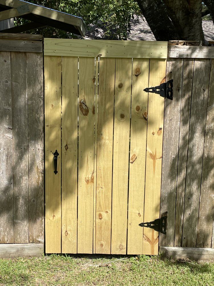 A new light-wood gate with black hinges and a handle, set within an older, weathered wood fence.
