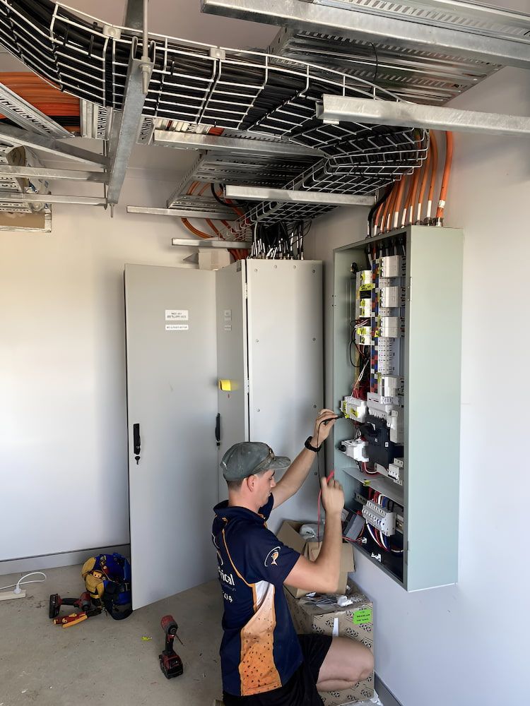 A Man Is Working On An Electrical Box In A Room — Reef Electrical in Cannonvale, QLD