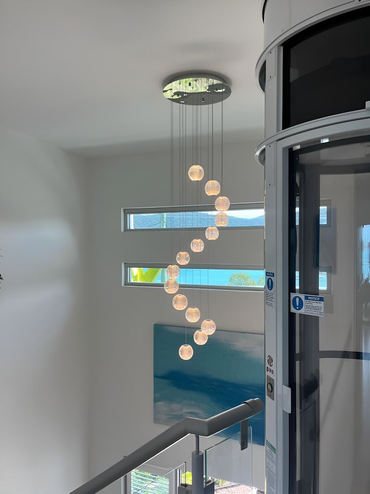 A Spiral Staircase With A Ceiling Light Hanging From It — Reef Electrical in Cannonvale, QLD