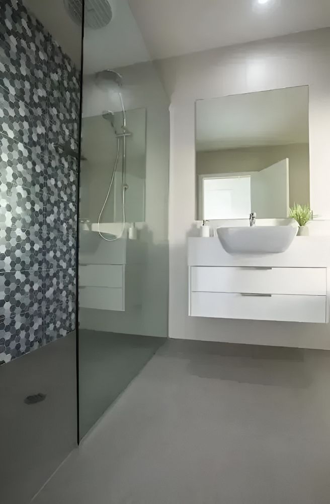 A Bathroom With A Sink, Mirror And Walk In Shower — Reef Electrical in Cannonvale, QLD