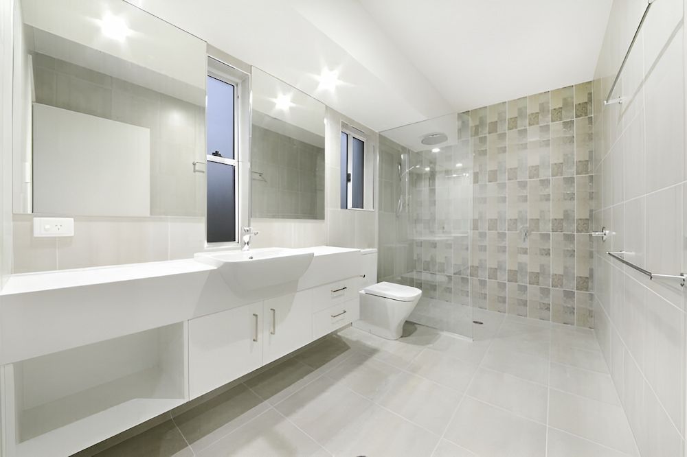 A Bathroom With Two Sinks, A Toilet, And A Walk In Shower — Reef Electrical in Cannonvale, QLD