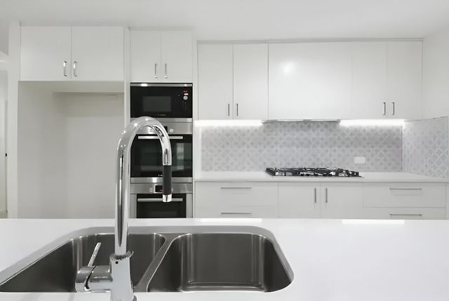 A Kitchen With White Cabinets And A Stainless Steel Sink — Reef Electrical in Cannonvale, QLD