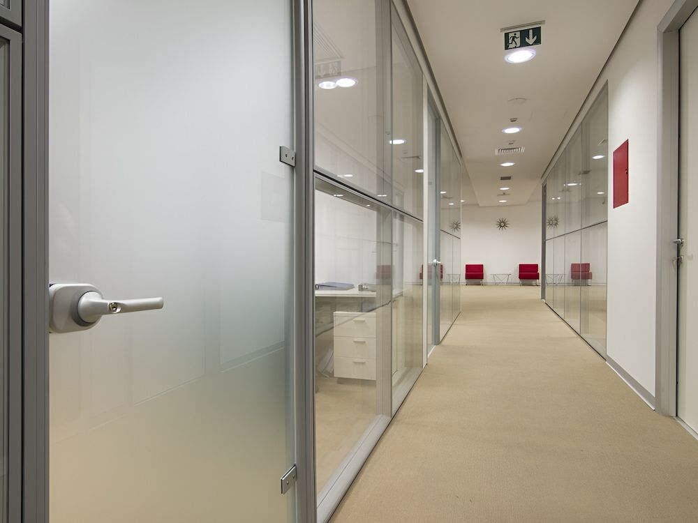 A Long Hallway With Glass Walls And Doors In An Office Building — Reef Electrical in Cannonvale, QLD