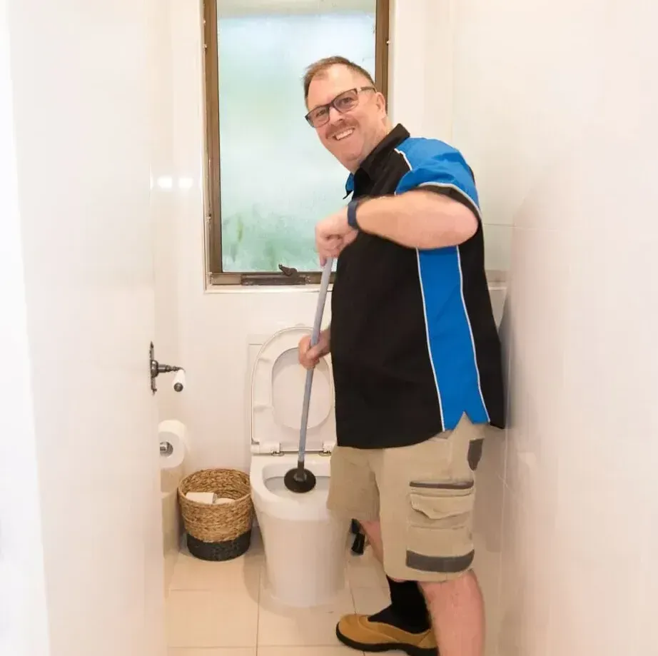 A man is standing in a bathroom holding a plunger  — Jobs2BDone in Woy Woy, NSW