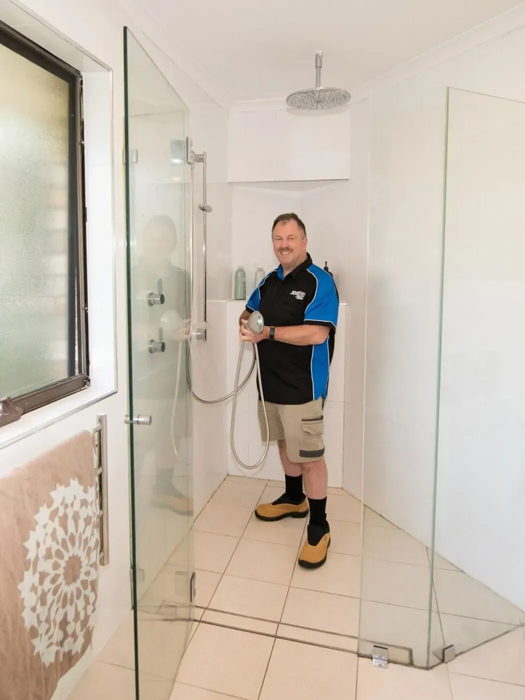 A man is standing in a shower holding a shower head — Jobs2BDone in Bensville, NSW