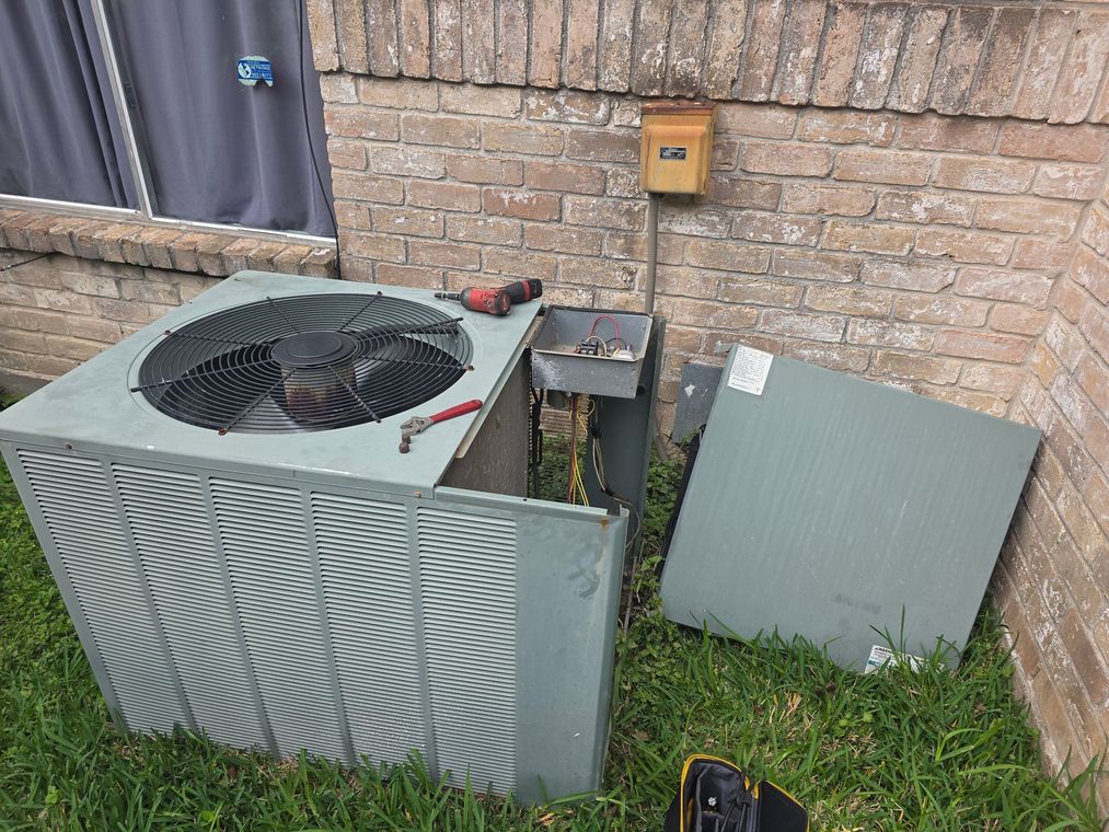 Technician testing an outdoor air conditioner unit with a multimeter and screwdriver