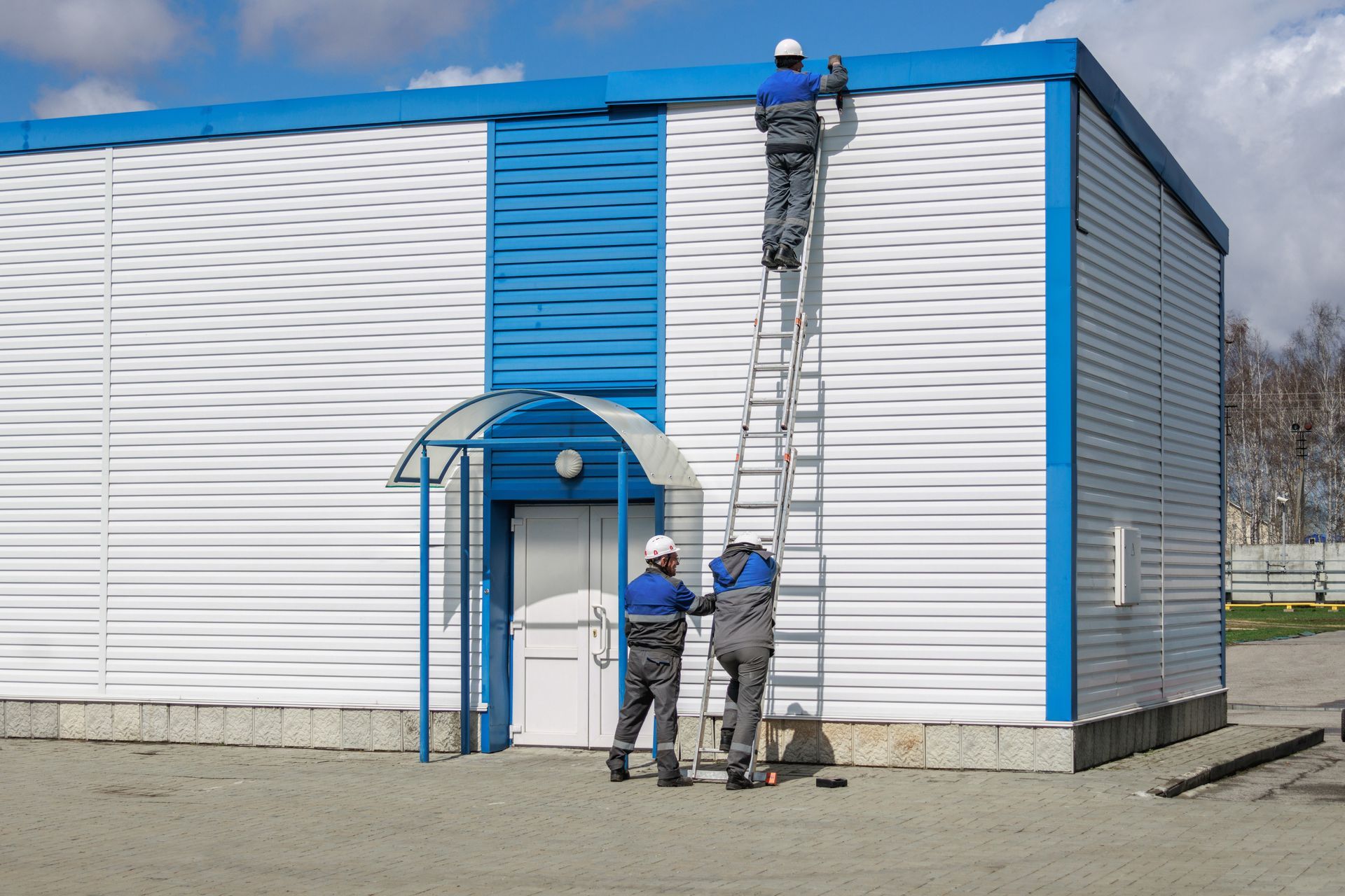 Workers are painting the exterior of a commercial building.