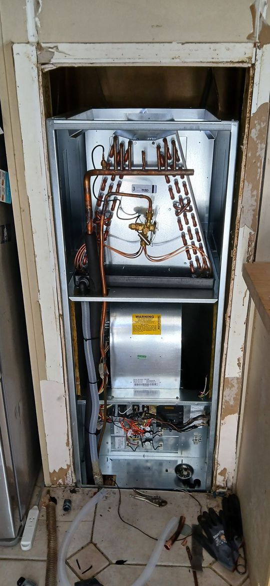 Open wall electrical panel with exposed wiring and circuit components, surrounded by damaged drywall.