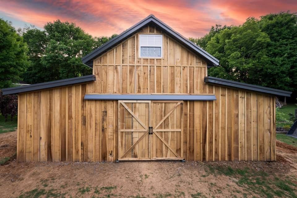 A wooden barn with a sunset in the background