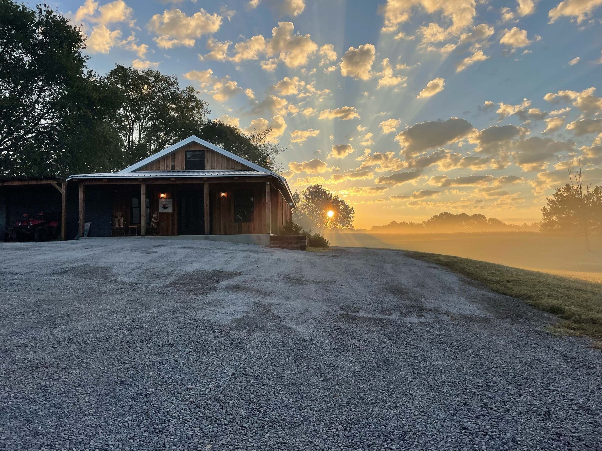 The sun is shining through the clouds over a house.