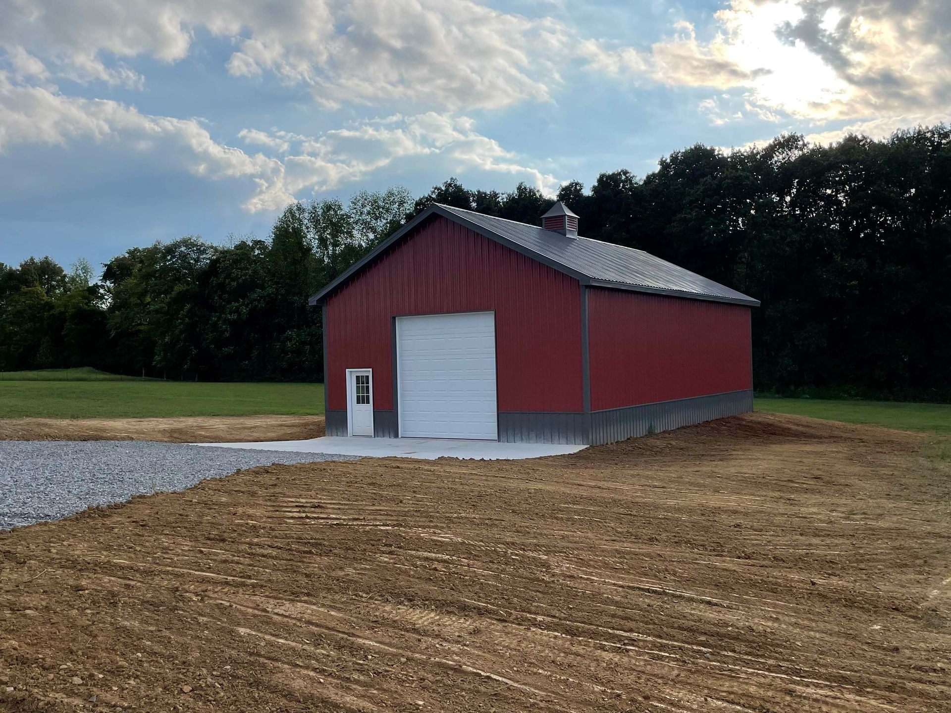 A red barn is sitting in the middle of a dirt field.