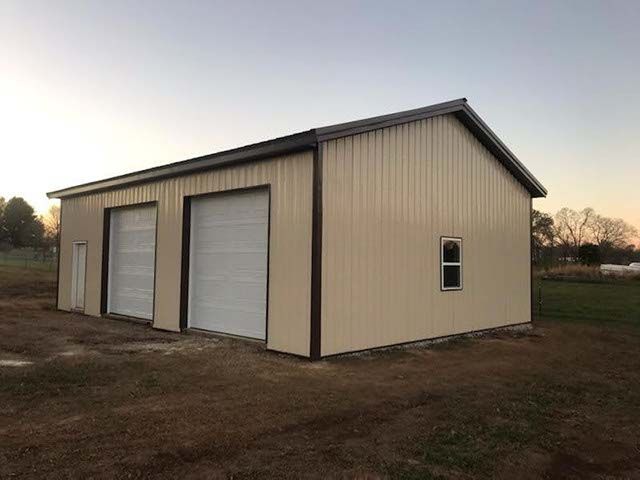 A large metal garage with two garage doors and a window.