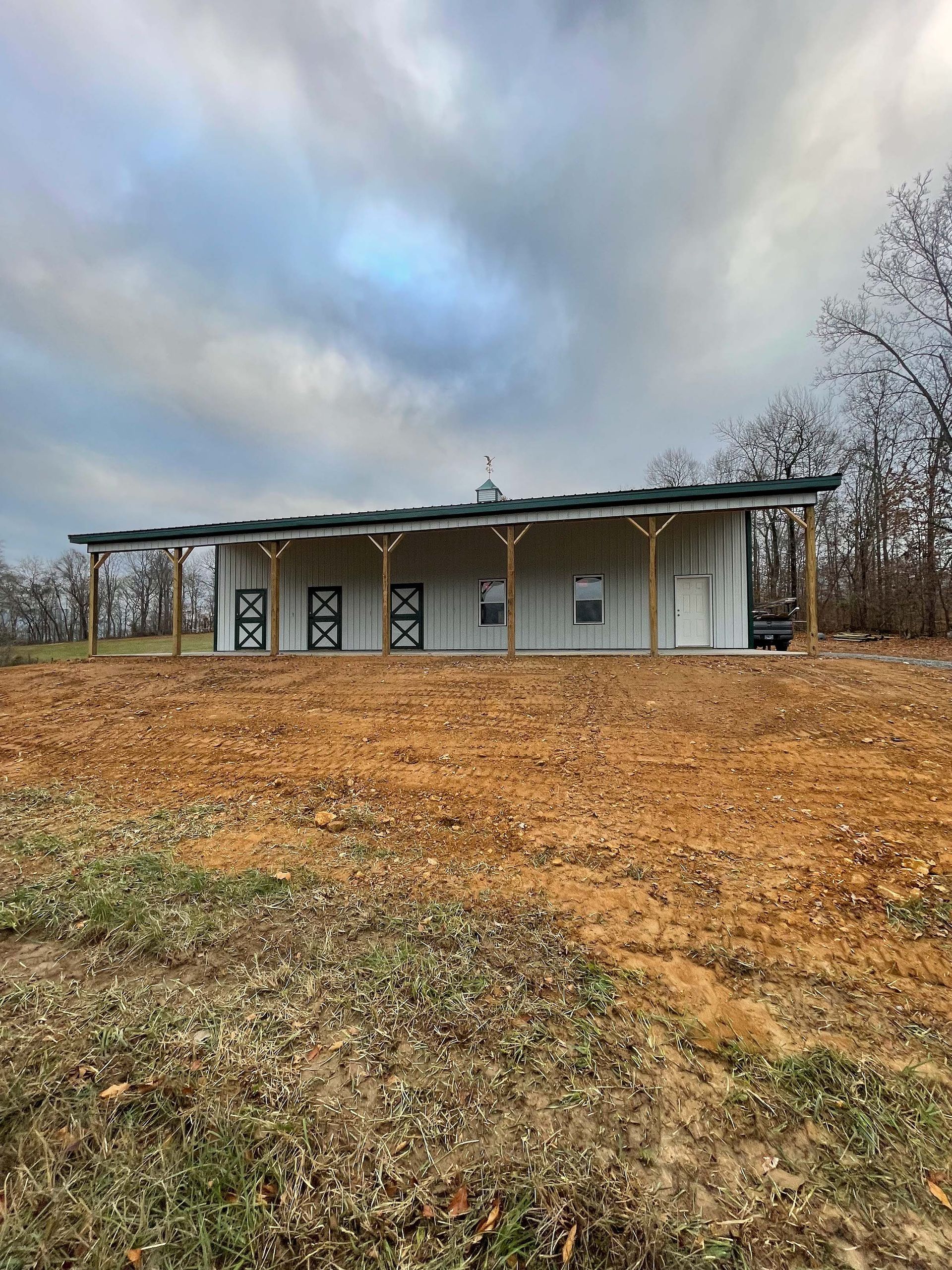 A white house is sitting in the middle of a dirt field.