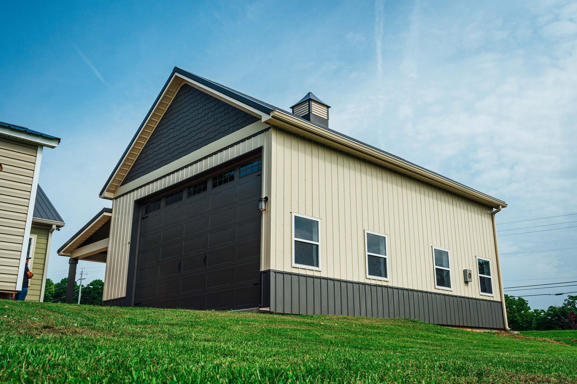 A large barn is sitting on top of a lush green hillside.