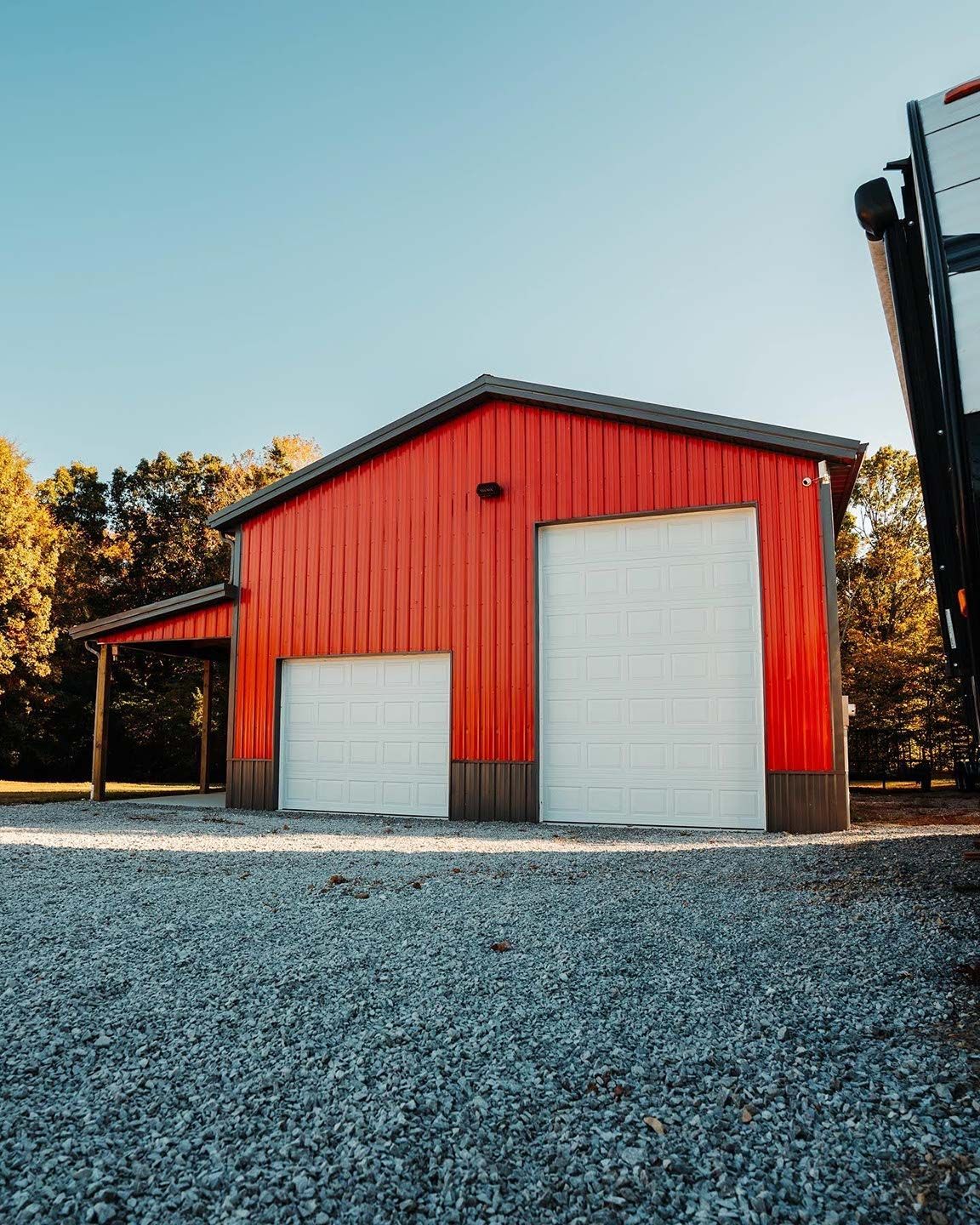 A red garage with white garage doors and a forklift parked in front of it.