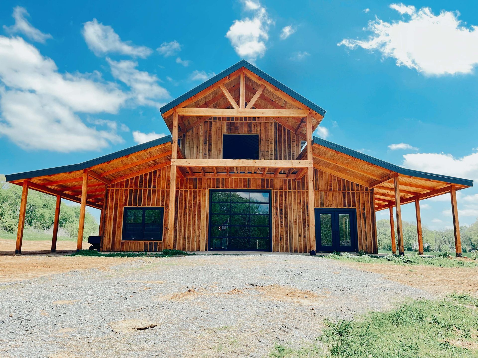 A large wooden barn is sitting on top of a dirt field.