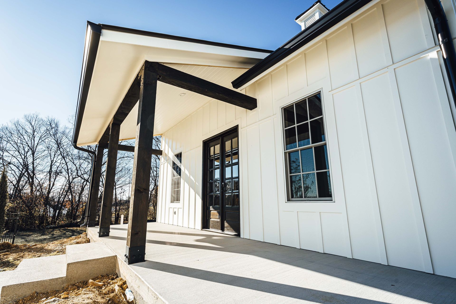 A white house with black trim and a porch.